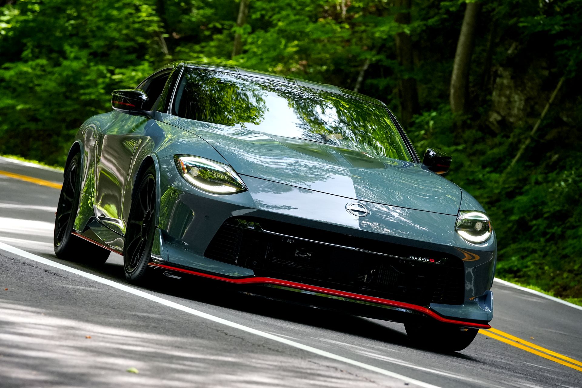 Grey Nissan Z Nismo driving on a tree-lined road